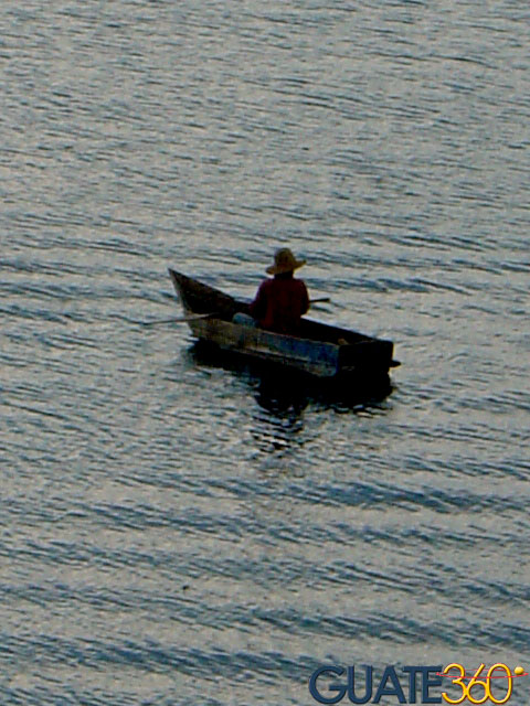 Pescador en cayuco bajo la lluvia